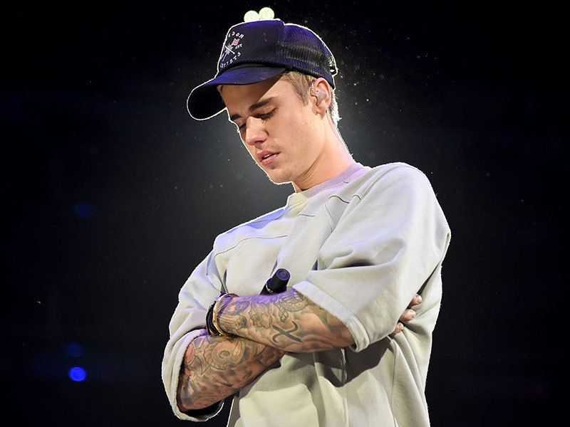Justin Bieber palco Primeira apresentação músical depois que Justin saiu da cadeia. O cantor está vestindo um moletom cinza, boné preto e segurando um microfone.
