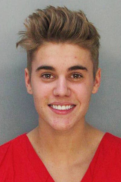 Justin Bieber na cadeia Imagem do Justin Bieber na prisão. O cantor está sorrindo e vestindo uma camiseta na cor laranja.